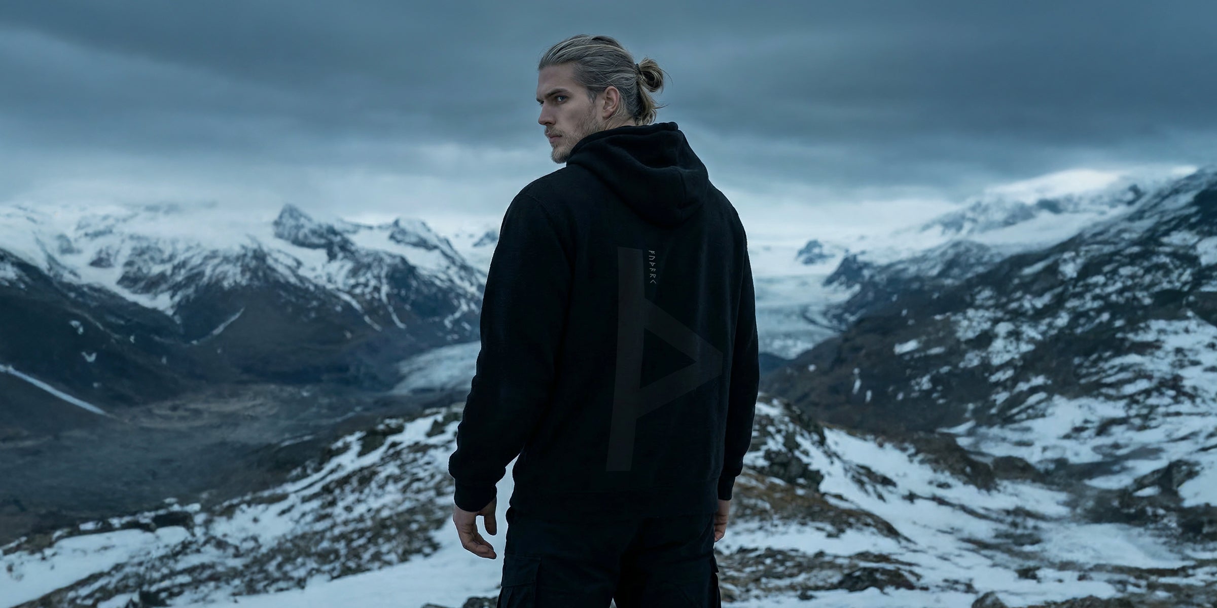 Black minimalist hoodie featuring a large Thurisaz rune printed on the back, symbolizing protection and raw force. Clean silhouette with relaxed fit, matte fabric texture, and subtle streetwear aesthetic, photographed from a partial rear angle with soft, moody lighting.