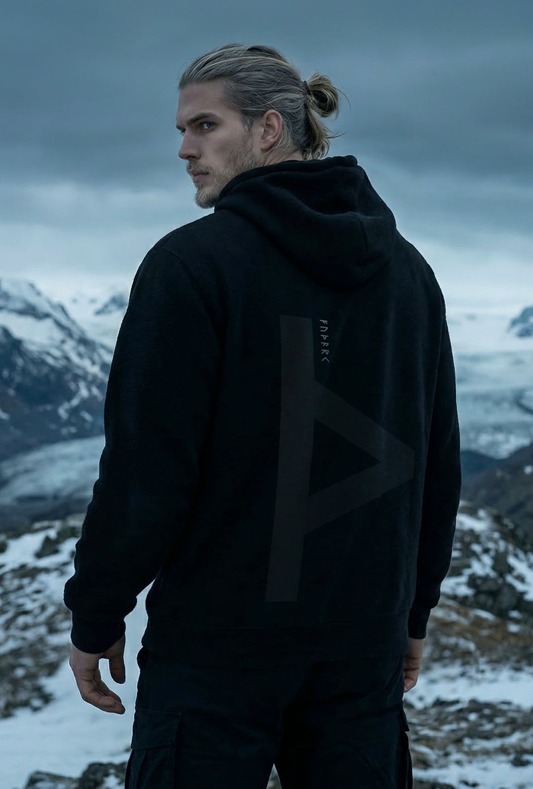 Black minimalist hoodie featuring a large Thurisaz rune printed on the back, symbolizing protection and raw force. Clean silhouette with relaxed fit, matte fabric texture, and subtle streetwear aesthetic, photographed from a partial rear angle with soft, moody lighting.
