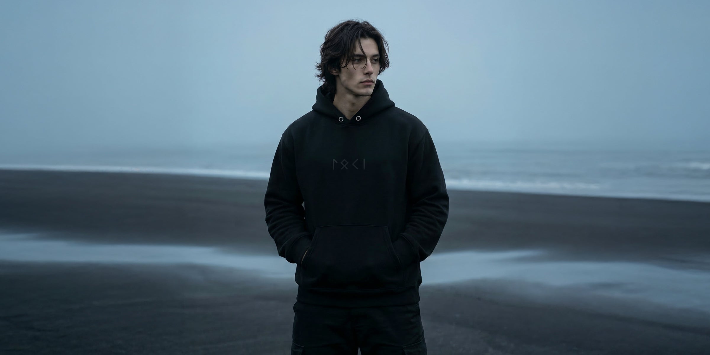 Black minimalist Loki hoodie featuring the name “Loki” spelled out in Elder Futhark runes. Sleek Norse-inspired design with subtle runic detailing, pullover style, adjustable hood, and kangaroo pocket.